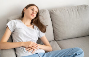 female with her hands over her stomach, experiencing pregnancy symptoms